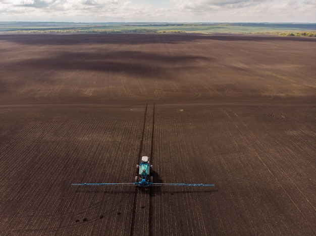 Spring agricultural work in the fields the tractor sprays crops with herbicides insecticides and pesticides