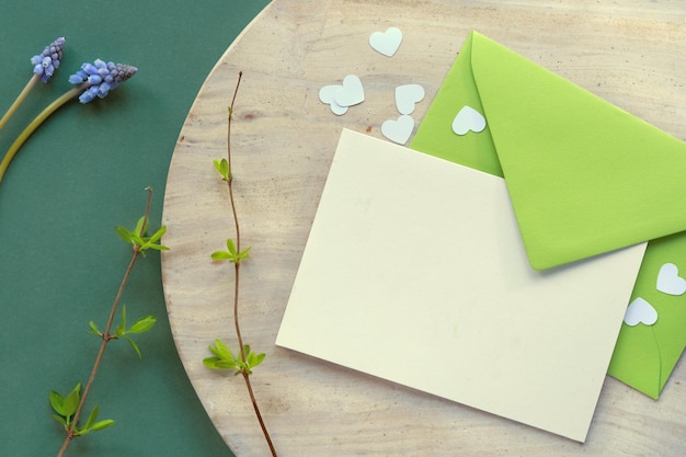 Spring background in shades of green Paper envelope with blank greeting card and heart confetti