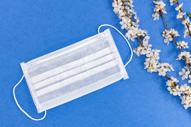 Spring blooming branches and medical mask on a blue background