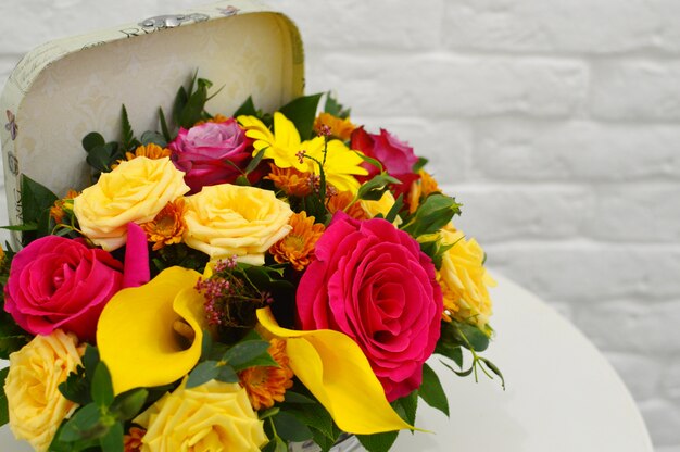 Spring bouquet of flowers in stylish hat box on white table.