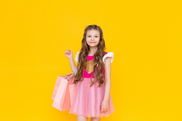 Spring discounts on summer goods in a children's store A little girl in a beautiful pink dress holds bags full of new things