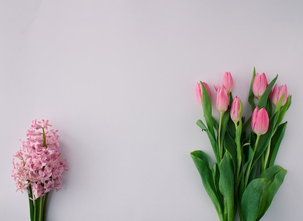 Spring floral arragement with pink tulips and pink hyacinth on bright background. Minimal concept. Copy space.