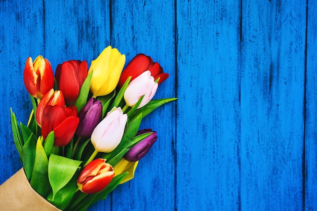 Spring flowers bouquet Beautiful tulips on rustic wooden bright color turquoise blue background Flat lay top view copy space