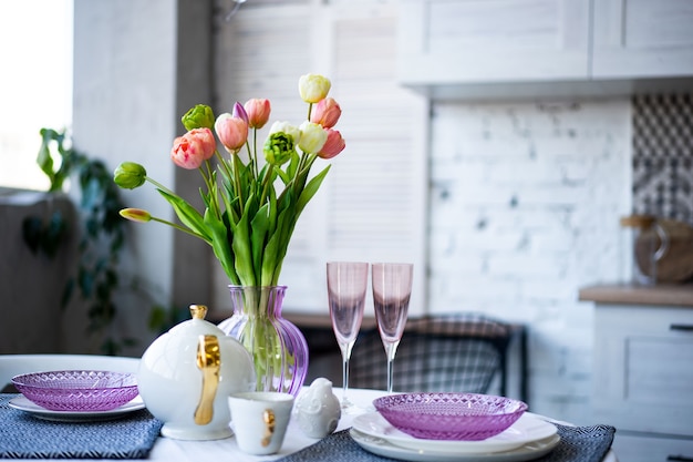 Spring flowers bouquet with beautiful purple glass crockery in the kitchen