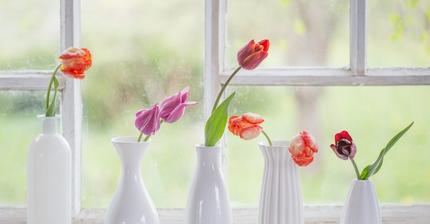 Spring flowers in white vase on old windowsill