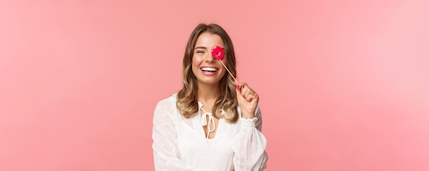 Spring happiness and celebration concept Closeup portrait of funny and carefree young beautiful blond girl having fun at party with girlfriends holding lips stick and laughing pink background