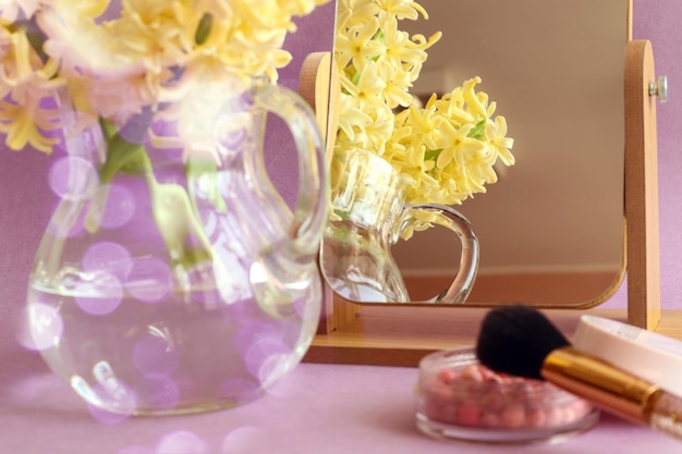 Spring is a time of good mood reflection of a bouquet of yellow hyacinths in the mirror powder and brush on a pastel background bokeh closeup