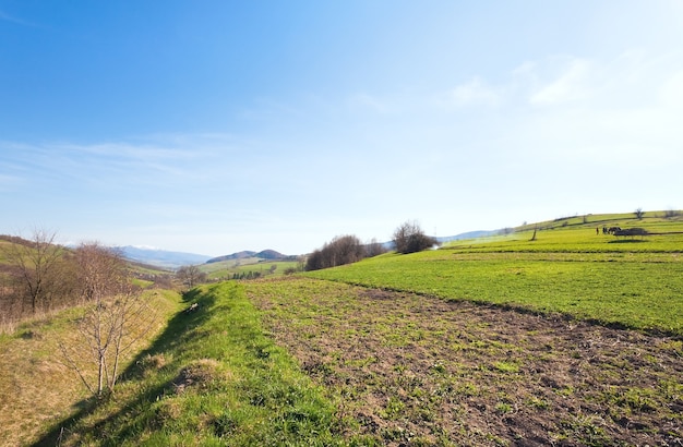 Spring mountain country valley view with farm fields and mountains in far