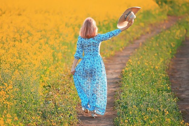 spring nature young girl in a field of flowers, freedom and happiness of a lady in a sunny landscape