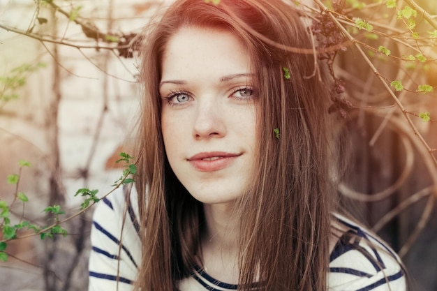 Spring, people, youth and beauty concept - Outdoors portrait of beautiful woman with brunette hair and makeup naturally. red highlight on the background