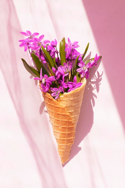 Spring pink flowers in a waffle cone on a pink background Creative spring idea