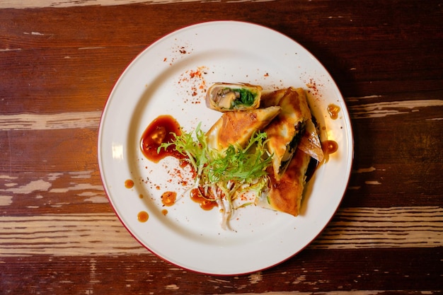 Spring rolls in filo dough with mushrooms and chuka PanAsian oriental cuisine on wooden table