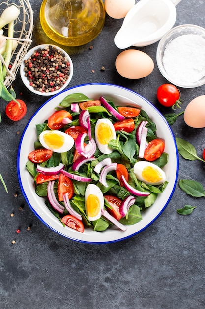 Spring salad. Salad with spinach leaves, tomatoes and boiled egg. Proper nutrition. Healthly food. The taste of summer. Raw ingredients in a snack