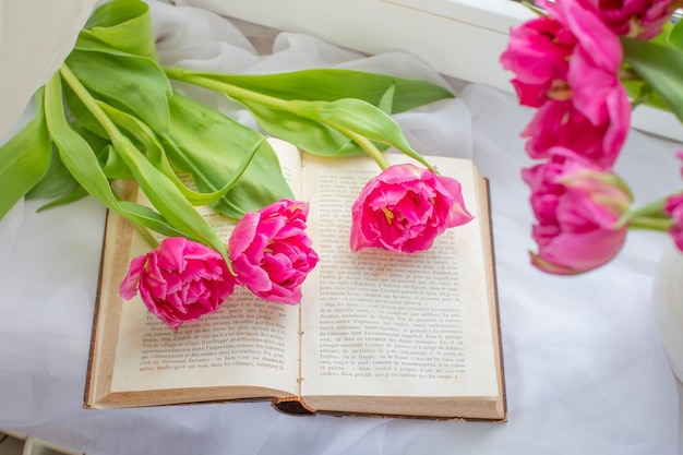 spring still life a bouquet of tulips a cup of tea an old French book on the window