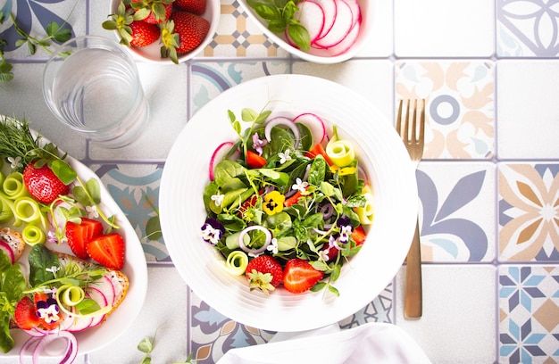 Spring summer salad with edible flowers pansy viola and fresh microgreens greens and strawberries