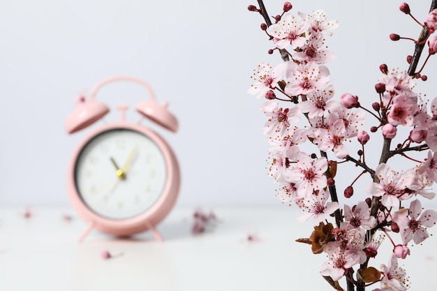 Photo spring time compositoh with alarm clock and twigs against white background space for text