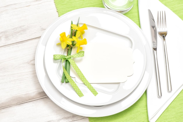 Spring time table decoration with narcissus flowers White plate fork knife