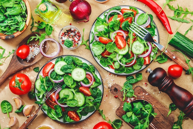 Spring vegetable salad with green spinach red tomatoes cucumber corn salad and onion Healthy vegan food Stone kitchen table background Top view