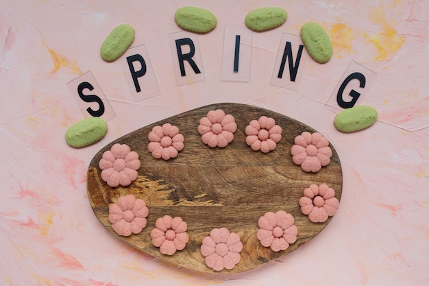 SPRING word and flower cookies on a wooden board on a pink background Spring holidays cooking concept