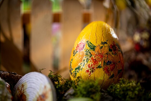 Photo springtime easter composition handcrafted yellow egg on moss with wooden fence background