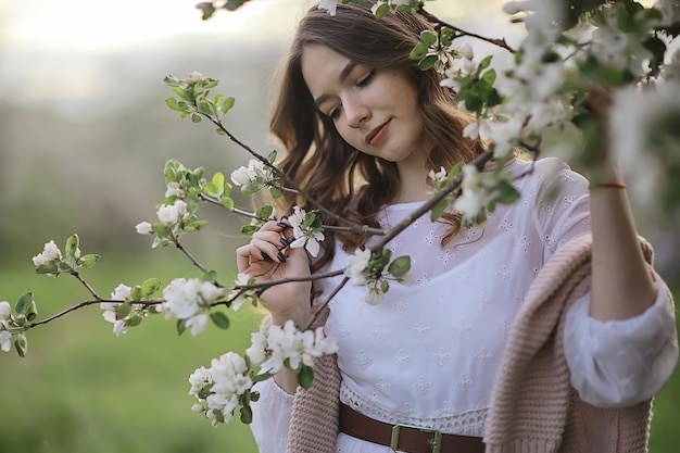 springtime fashion portrait of a young girl in a blooming cherry garden, tenderness of the morning