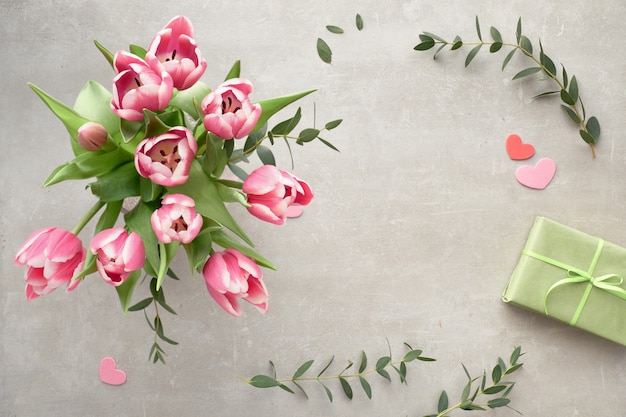 Springtime flat lay with bunch of pink tulips, eucalyptus leaves and gift boxes