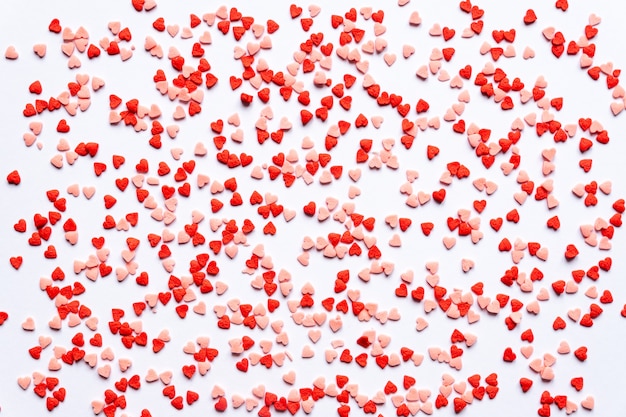 Sprinkles background, sugar sprinkle red hearts, decoration for cake and bakery. Top view, flat lay. Valentines holiday.