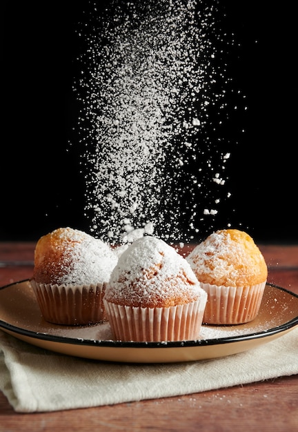 Sprinkling icing sugar over freshly baked muffins, homemade cakes.