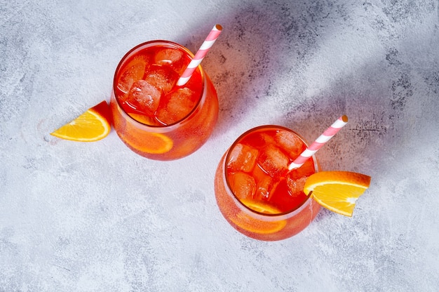 Spritz Cocktail in glasses with ice and orange slice on light blue background