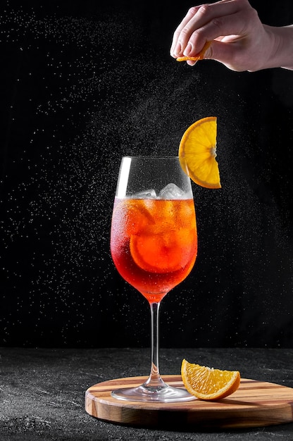 Spritz Cocktail in wine glass on wooden board on dark background