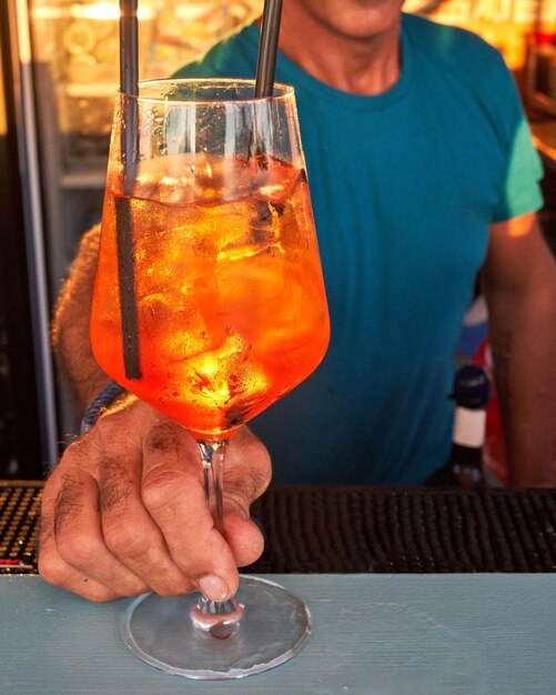 Spritz traditional cocktail with alcohol being prepared by unrecognizable man in a beach bar European summer drink Italian drink Lifestyle concept