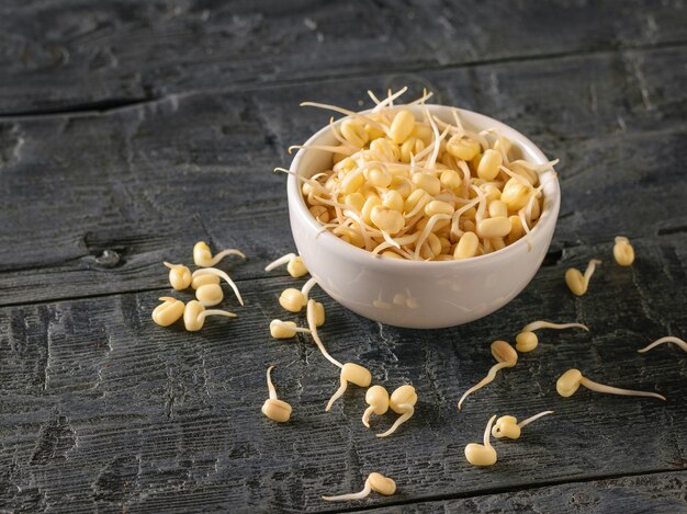 Sprouted mung beans in a ceramic bowl on a black wooden table