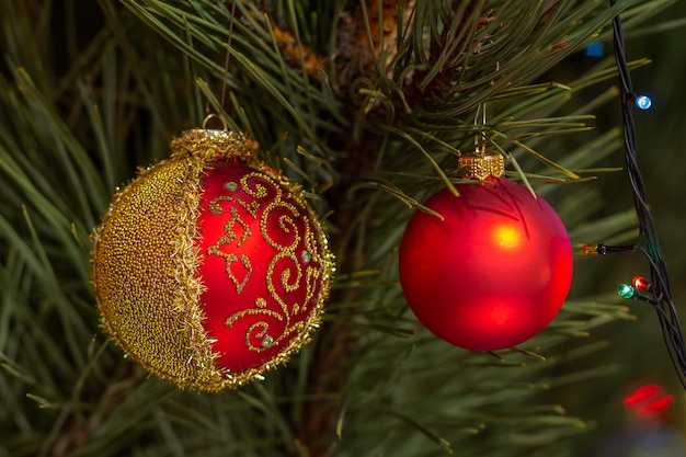 Spruce branch with Christmas balls and festive lights on the background