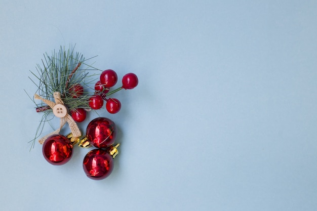 Spruce branch with rowan berries on a blue background. Scenery for the holiday of Christmas.