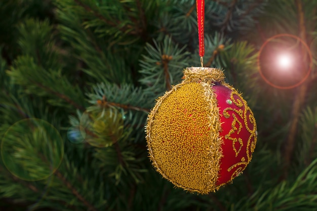 Spruce branch with toy ball and festive lights with sparkles on the background. Christmas and New Year concept.