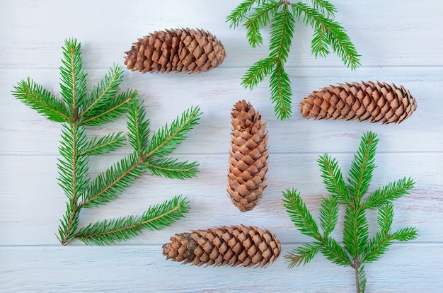 Spruce branches and cones are laid out on blue painted wooden surface