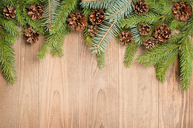 Spruce branches and coniferous cones on a wooden background, top view