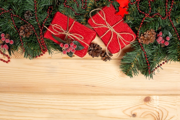 Spruce branches with Christmas ornaments and gift on wooden