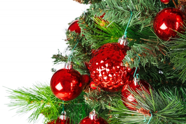 Spruce branches with red baubles against white background