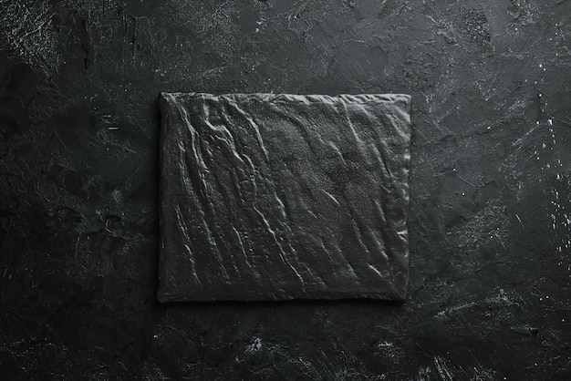 Photo square black stone dish on a black stone background top view free space for your text