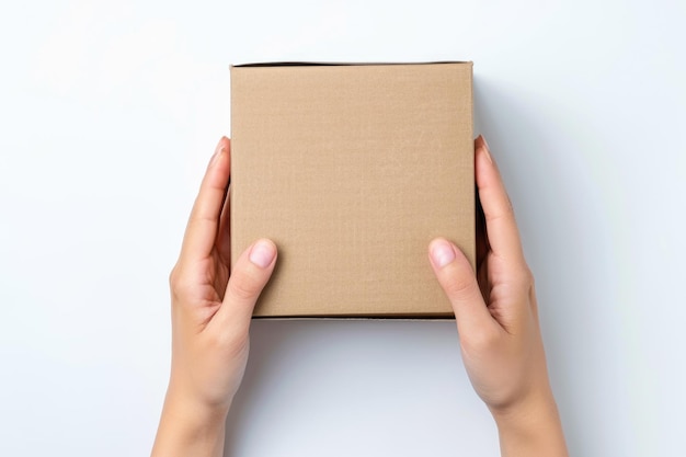 Square cardboard box in female hands Top view white background