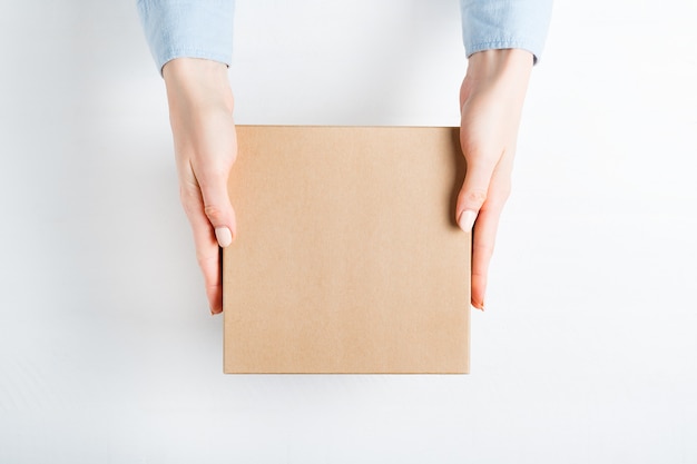 Square cardboard box in female hands. 