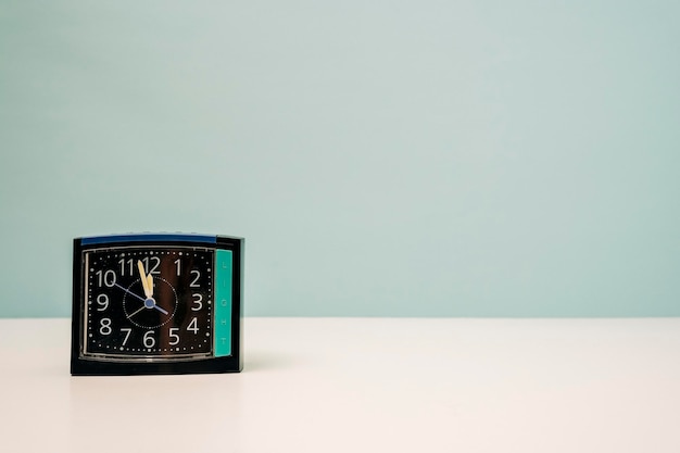 Square modern alarm clock on the table on a turquoise background time