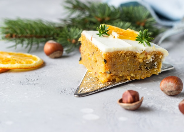 Square pieces of raw spiced carrot cake with orange, nuts and cream cheese frosting. 