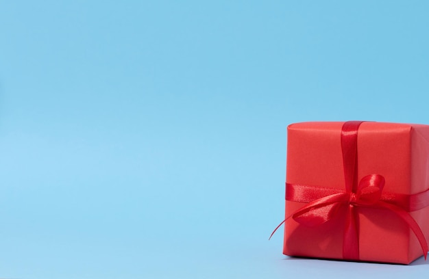 A square red gift box with a red ribbon on a blue background congratulatory backdrop surprise