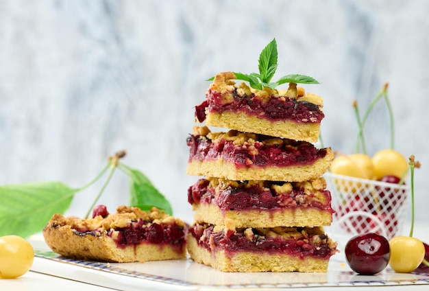 Square slices of cherry crumble lie in a stack on a white board