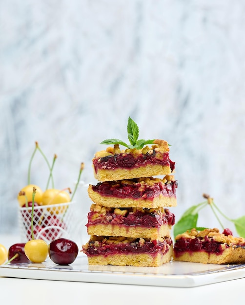 Square slices of cherry crumble lie in a stack on a white board