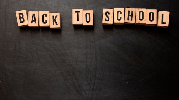 Square wooden letters with the phrase quotBack To Schoolquot written in English on a black chalkboard background