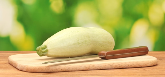 Squash on a cutting board on wooden table on green background closeup