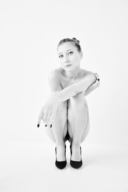 Squatting naked girl with crossed arms